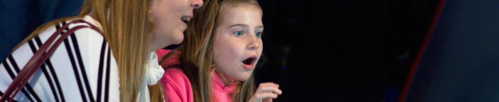 mother and daughter playing videogame - daughter has a shocked face